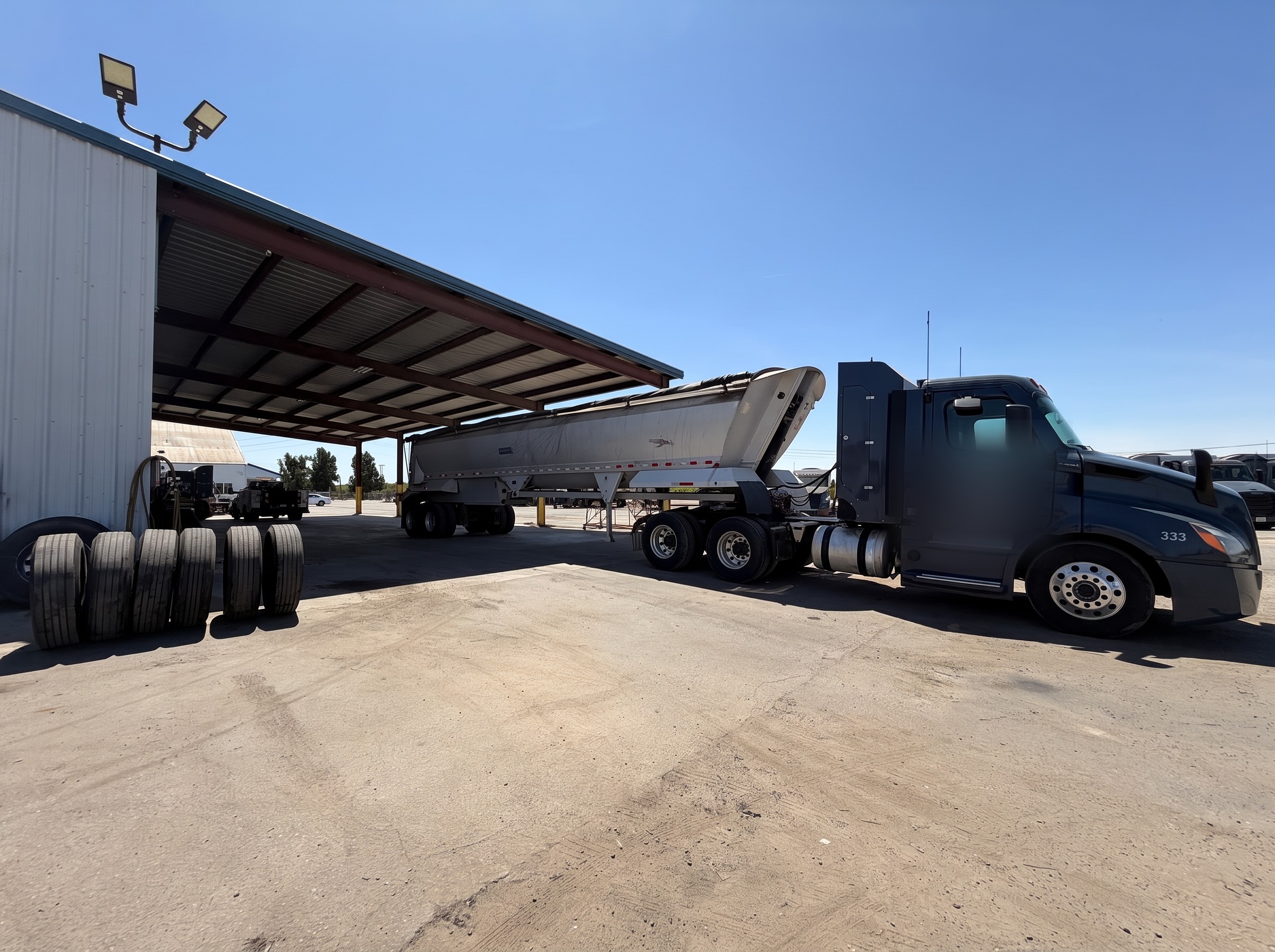 End-dump trailer and truck backed under the loading shed at the All Seasons Logistics yard
